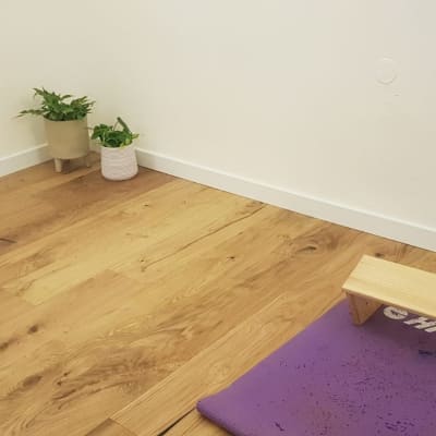 רצפת פרקט עץ עם שטיח סגול וספסל עץ קטן