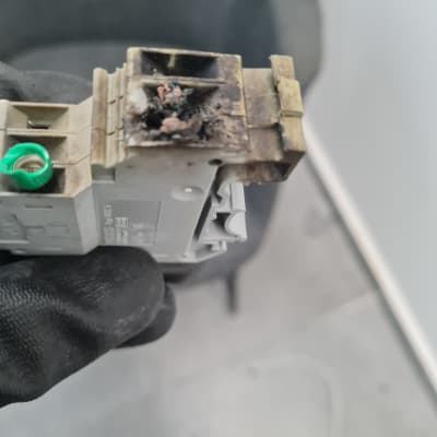 חלק חשמלי שרוף מוחזק בכפפה שחורה