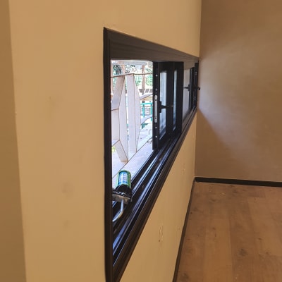 חלון אלומיניום עם מסגרת כהה וקיר בהיר