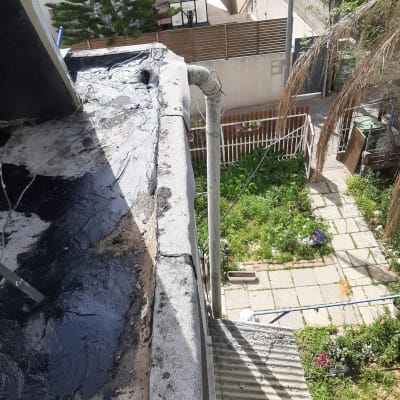 איטום גג עם חומר שחור ליד צינור ניקוז