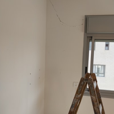 סולם ליד קיר עם סדקים לצביעת קיר