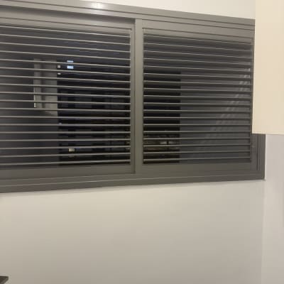 חלון עם תריסים אפורים על קיר לבן