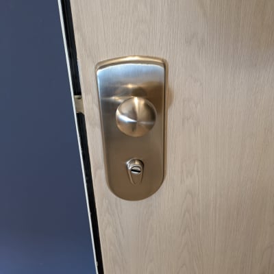 ידית דלת מתכתית על דלת עץ בהירה