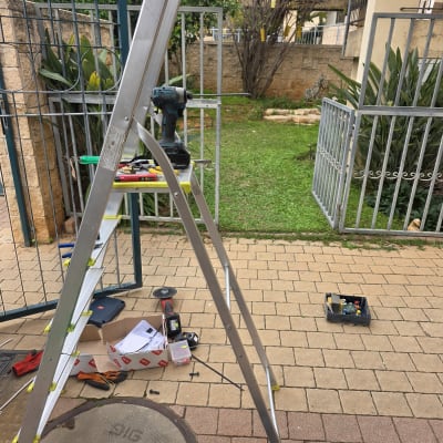 סולם וכלי עבודה ליד שער חשמלי