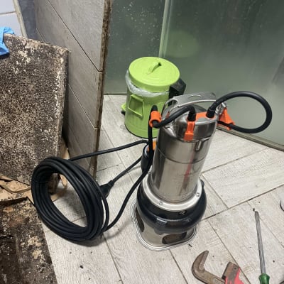 משאבה עם כבל, מפתח צינורות ומברג על הרצפה