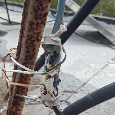 חוטי חשמל מחוברים לעמוד מתכת חלוד