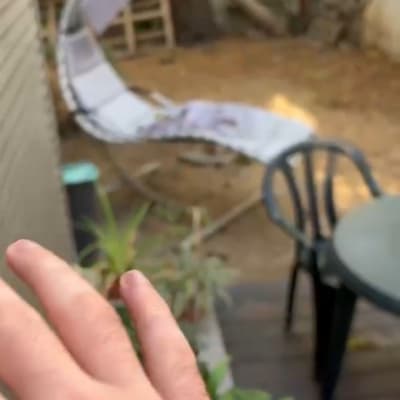 יד נעה ליד כיסא פלסטיק ושולחן בגינה