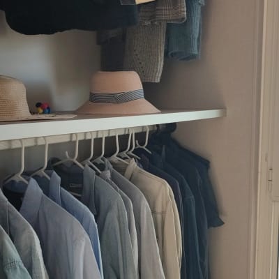 חולצות תלויות בארון עם כובעים על מדף
