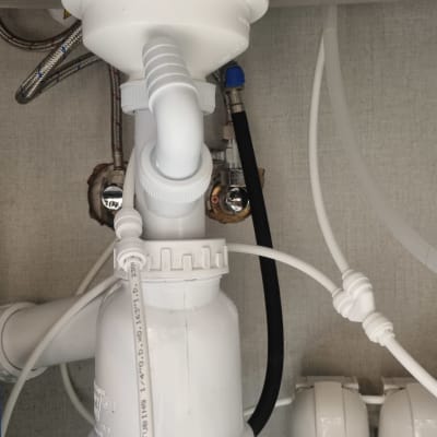 צנרת פלסטיק לבנה מתחת לכיור עם חיבורים