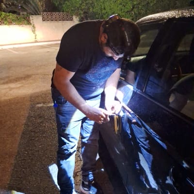 אדם פותח רכב עם כלי עבודה בלילה