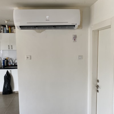 מזגן מותקן על קיר לבן עם תצוגת טמפרטורה