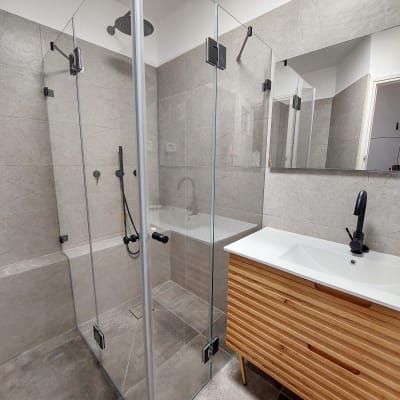 מקלחון זכוכית עם ראש מקלחת עגול על הקיר