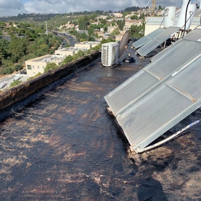 גג אטום בזפת עם קולטי שמש ומזגן