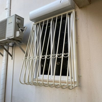 סורגי מתכת לבנים על חלון קיר חיצוני