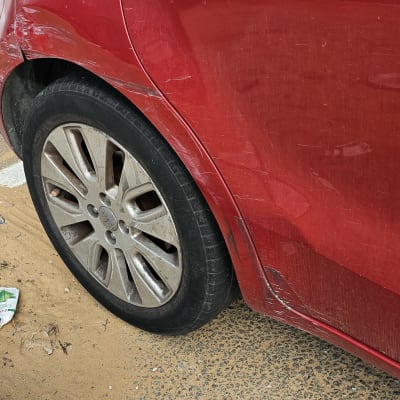 מכונית אדומה עם שריטות על הדלת והפגוש