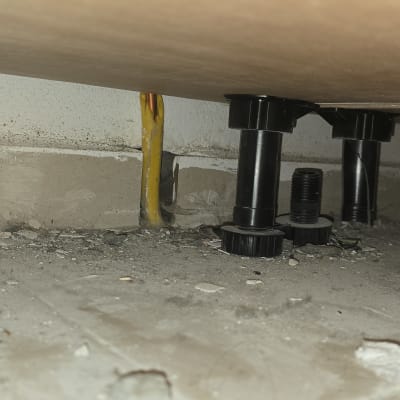 רגלי פלסטיק שחורות מתחת לרהיט על רצפה מאובקת