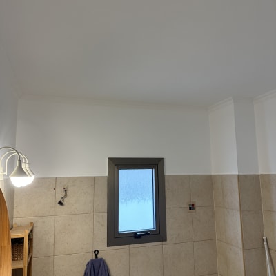 קיר צבוע בחדר עם חלון קטן ומנורה