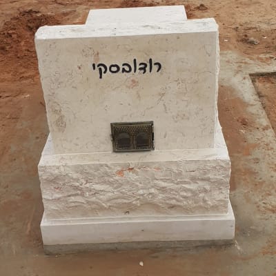 מצבה לבנה עם כיתוב בעברית על אדמה