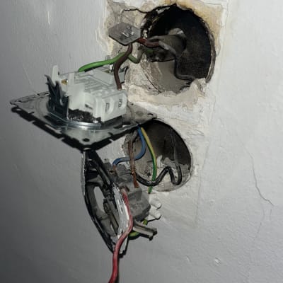 חוטי חשמל חשופים בקיר עם שקע פתוח