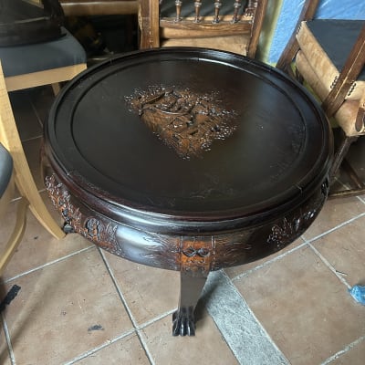 שולחן עץ עגול עם גילופים דקורטיביים על הרגליים