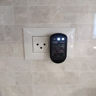 בודק חשמל מחובר לשקע בקיר