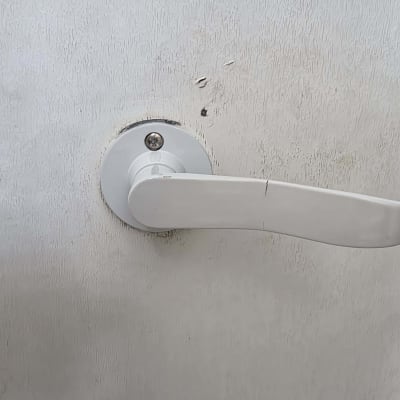 ידית דלת לבנה על רקע קיר בהיר