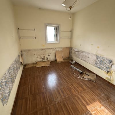 חדר ריק עם קירות מתקלפים ורצפת עץ