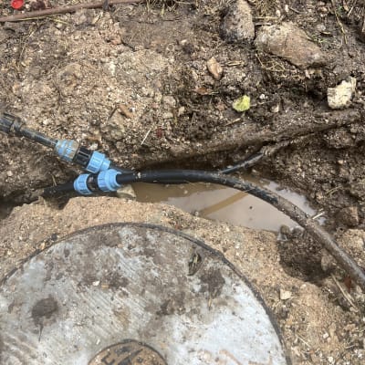צינורות פלסטיק כחולים ושחורים באדמה רטובה