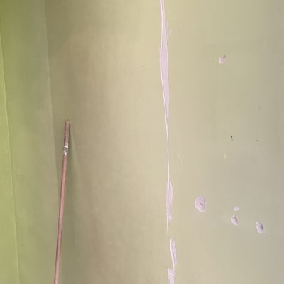 קיר צבוע עם תיקוני טיח ומקל צבע