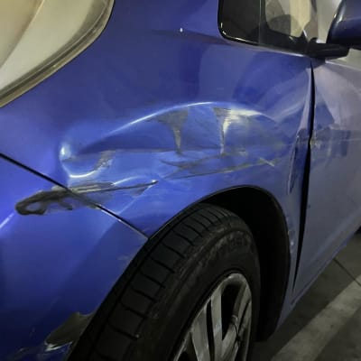 נזקי פחחות בצד רכב כחול עם שריטות ושקעים