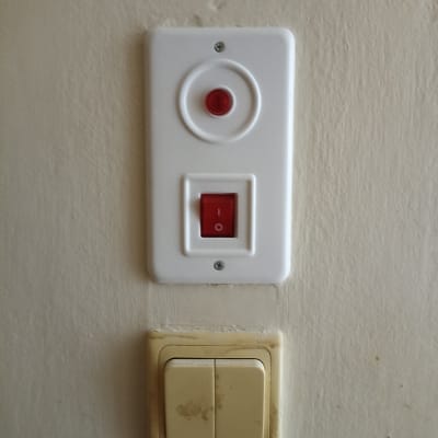 מתג חשמלי עם כפתור אדום על קיר