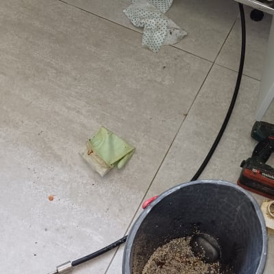 דלי עם לכלוך, צינור וכלים מתחת לכיור