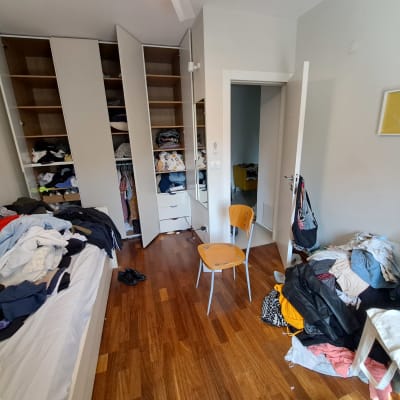 חדר עם ארון בגדים פתוח ובגדים מפוזרים על המיטה והרצפה