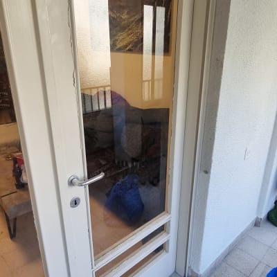 דלת זכוכית עם ידית מתכת ומסגרת לבנה