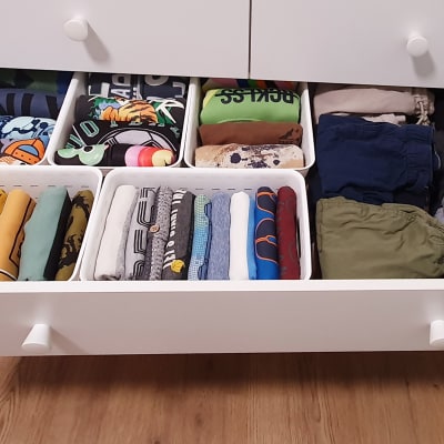מגירה פתוחה עם בגדים מקופלים ומאורגנים בסלים