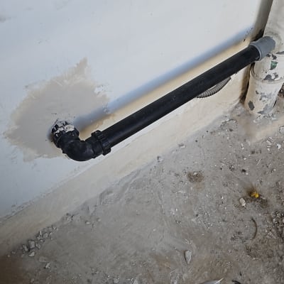 צינור שחור מותקן על קיר עם תיקוני טיח