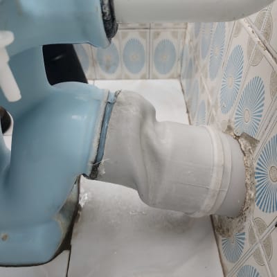 חיבור צינור לבן לאסלה כחולה עם אריחים ברקע