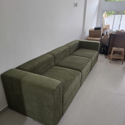 ספה ירוקה בחדר עם קופסאות קרטון