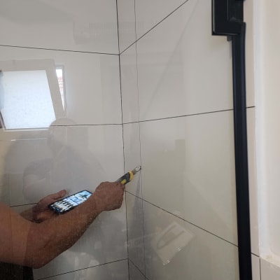 אדם בודק קיר אריחים עם כלי עבודה