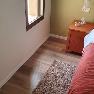 רצפת פרקט עץ בחדר שינה עם שטיח קטן
