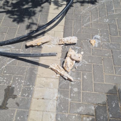 צינור שחור ושברי בטון על המדרכה