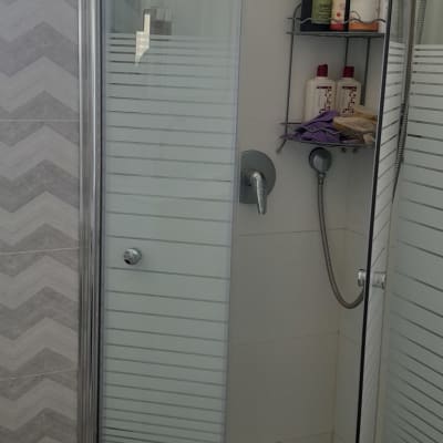 מקלחון עם דלת זכוכית, מדף עם בקבוקי שמפו וסבון