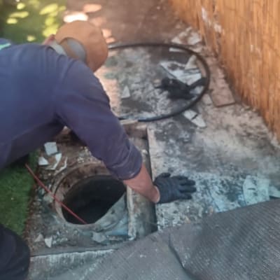 אדם עובד על צינור ביוב עם כלים