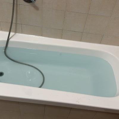 אמבטיה עם מים וצינור מתכת על קיר אריחים