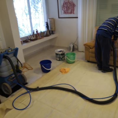 אדם מנקה ספה עם מכונת ניקוי ושואב אבק