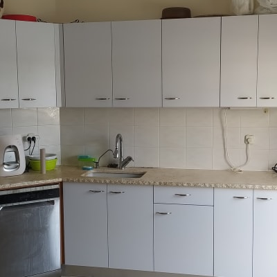 מטבח עם ארונות לבנים, כיור וברז, תנור ומדיח כלים