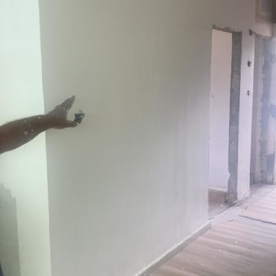 קיר משופץ עם יד מצביע על שקע חשמלי