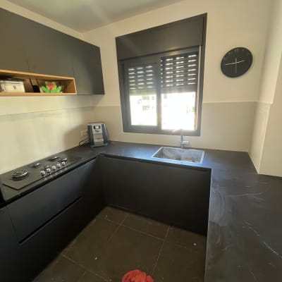 מטבח בשיפוץ עם משטחי עבודה כהים ומטלית אדומה על הרצפה