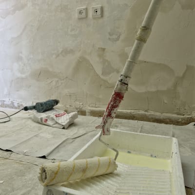 רולר צביעה במגש צבע, קיר עם טיח מתקלף