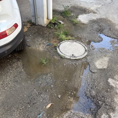 שלולית מים ליד מכסה ביוב בחניה